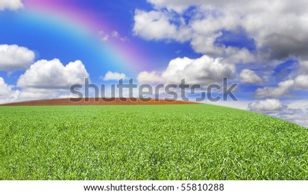 a Grass field hill with beautiful clouds, rainbow and sky
