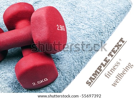 a Pair of red dumbbells on a blue towel with space for text