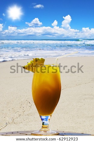 Tropical fruit cocktail on a empty open beach with beautiful sky