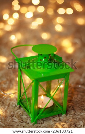 Green Christmas lantern on a beige carpet. Golden bokeh. New Year concept