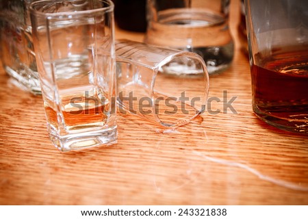 Glass, spilled whiskey and empty bottles on the bar. Abuse of alcohol hangover. Alcoholism concept. Drunk driver concept