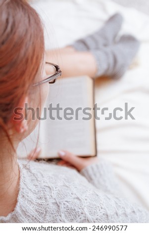 Soft photo of woman on the bed with old book  in hands, top view point