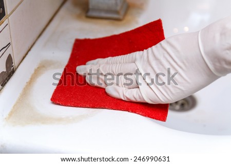 Hand in glove cleans dirty washbasin red sponge