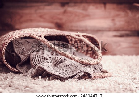 knitted fabric in a basket on a rug on a wooden background. vintage toning
