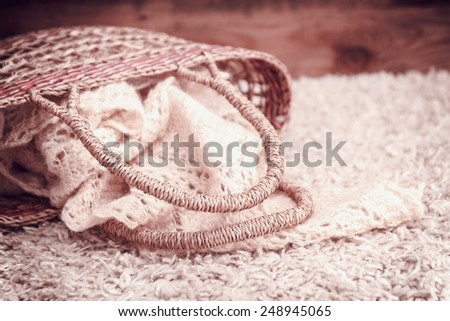 knitted fabric in a basket on a rug on a wooden background. vintage toning