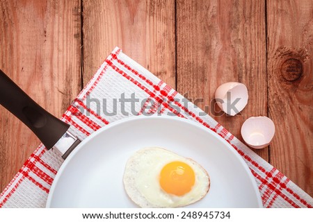 Scrambled eggs in a ceramic pan on old wooden table. Healthy food concept. top view