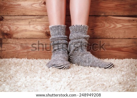 Legs of a woman in gray socks on the carpet on the wooden background. Vintage toning