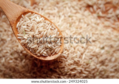 food background. brown rice in a wooden spoon. top view