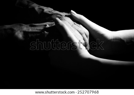 Hands of the old man and a young woman. Black and white. in low key