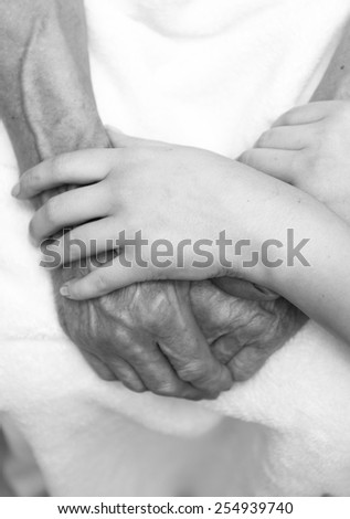 Hands of the old man and a young woman. Black and white. top view
