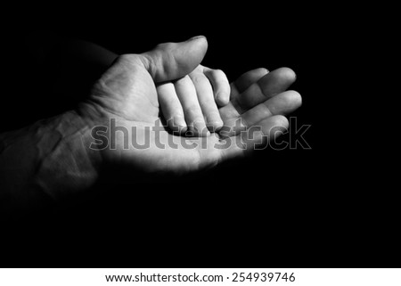 Hand of old and young man in a low key. black and white