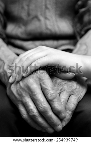 Hands of the old man and a young woman. Black and white.