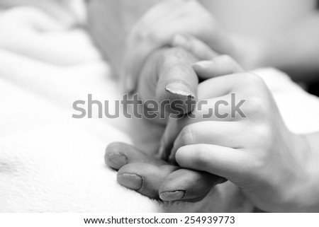 Hands of the old man and a young woman. Black and white. close up