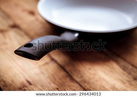 White ceramic pan with a black pen on the old wooden table.