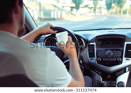 Man with a cup of coffee while driving. don\'t sleep and drive