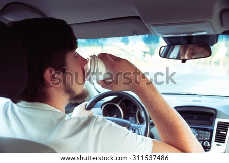 Man with a cup of coffee while driving. don\'t sleep and drive