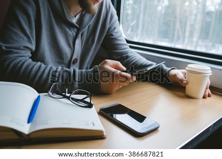 The man sits at a table in a train with a tablet in hands