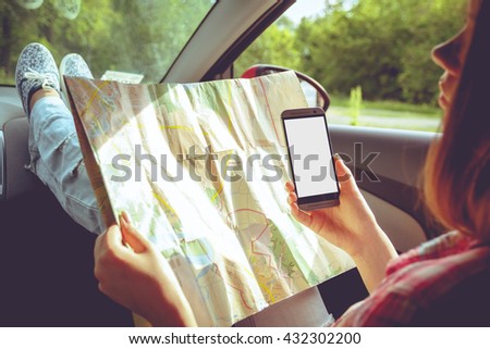 Girl with map and phone in hand in the car. Car travel, hitchhiking concept