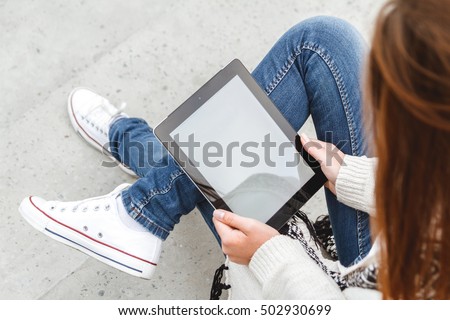Girl sitting with a tablet in hands. Top view. Remote operation concept. Online education students. Online shopping