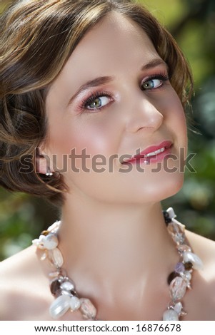 Young woman with pink make-up and green eyes in semi-precious stones necklace
