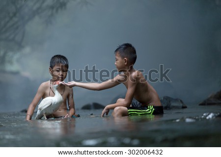 Boys playing with ducks in the stream of life in rural Thailand Ban Wang Muang district\'s Tambon Nong Khai, Thailand Sang Khom.
