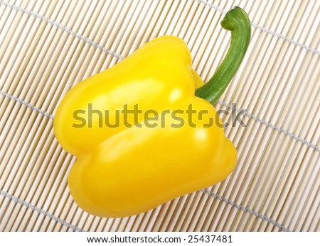 Yellow bell pepper laying on japanese wooden mat.