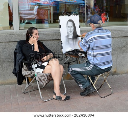MOSCOW, RUSSIA - JULY 18, 2013: Street artist draws a girl on famous Arbat in Moscow, Russia