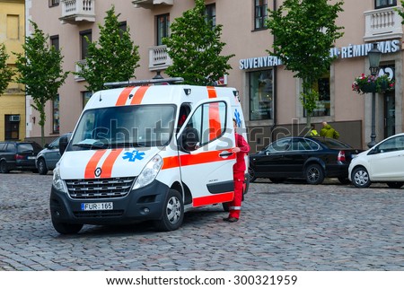 KLAIPEDA, LITHUANIA - JULY 11, 2015: Medical worker in overalls stands near the cabin of ambulance car on the street of Klaipeda, Lithuania