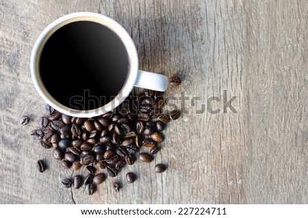 Black coffee with beans in the upper left corner on grained wood top view