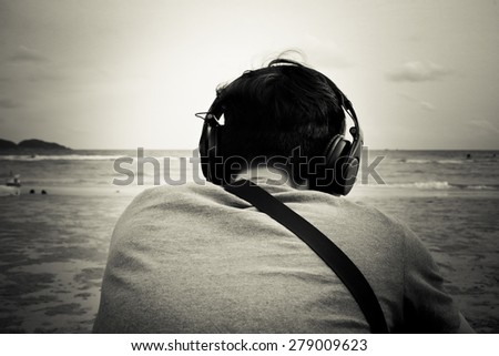 young man listening music on the beach (black and white)