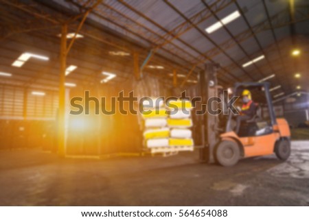 blur warehousing. Forklift driver stacking pallets with cement packs by stacker loader