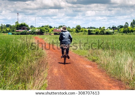 old man ride bicycle back from rice farm,thailand