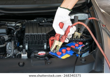 automotive technician charging vehicle battery