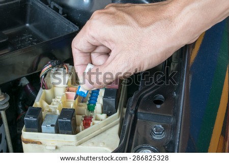 Auto mechanic checking a car fuse