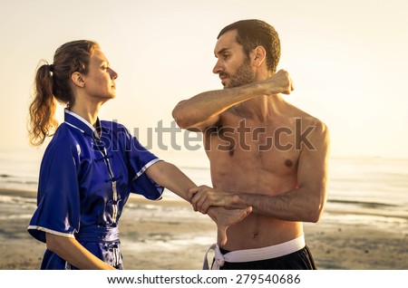 challenge between a student of martial arts and his teacher at the beach during sunrise - lifestyle concept