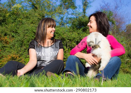 couple of friends playing with their dog - people, animal and lifestyle concept