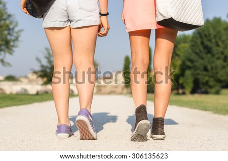 two girls walking together in the park, close-up on the feet - people, lifestyle and nature concept