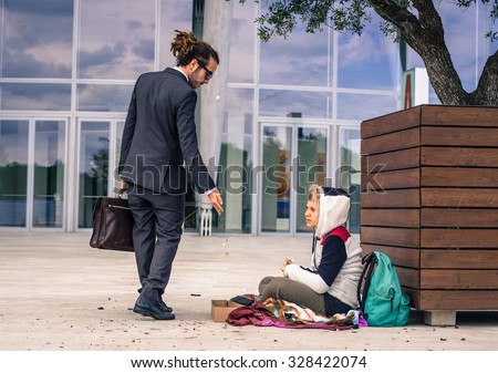 Businessman helps a homeless giving money - business, people and lifestyle concept - caucasian people