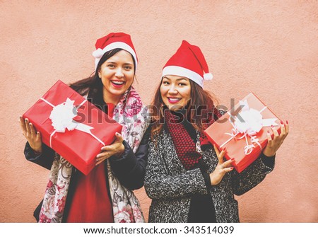 Happy Christmas - two girls are smiling with their gifts - asian and caucasian people