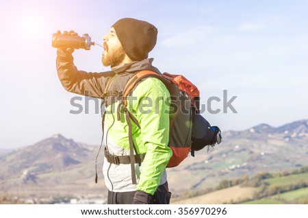 hiker in the mountains drinking water from his water bottle - caucasian people - people, drink and nature concept