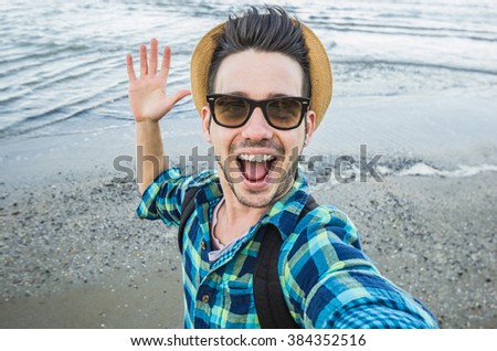 Handsome caucasian guy takes a selfie at the beach - people, lifestyle and technology concept