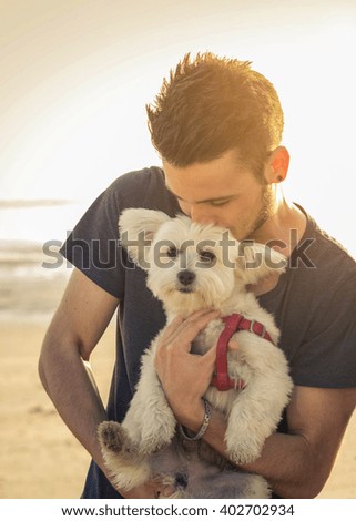 Attractive caucasian man is kissing his dog at the beach - concept about animals, people and lifestyle