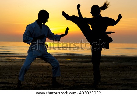 Artial marts fight between master and his pupil at the beach during the sunrise - silhouette - concept about people, lifestyle and sport