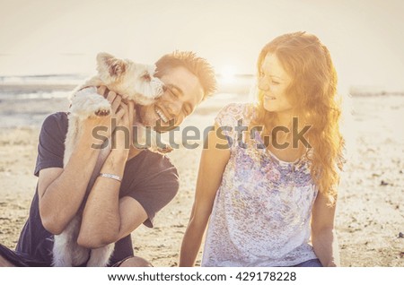 Loving couple playing with dog at the beach. Concept about love, animal and lifestyle