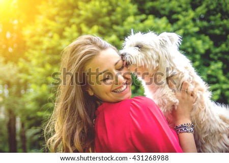 Puppy white dog licking it\'s owner. Attractive caucasian girl having fun with her dog