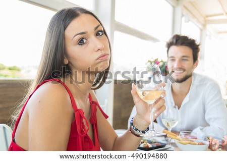 Young woman making an exasperated expression gesture on a bad date at the restaurant