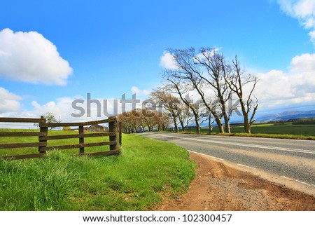 Rural road, wooden fence and blue sky