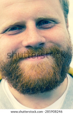 Young red bearded hipster looking into camera and smiling