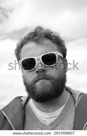 Young bearded hipster looking into camera in black and white