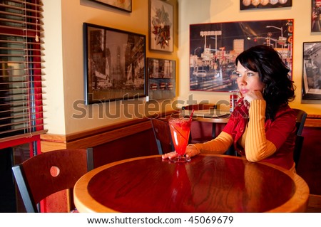 Young pretty girl is waiting for somebody in fast food restaurant